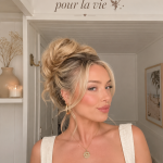 Une femme réalisant un messy bun élégant, style décontracté.